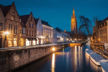 Akşam yağmurdan sonra Bruges sokaklarında. Onze Lieve 'in gece manzarası. Brugge, mavi gökyüzünün arka planına karşı. Belçika.