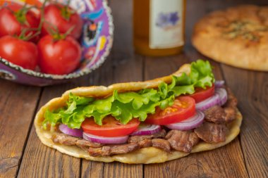 Kavrulmuş et, domates, soğan ve marul mutfak masasında lezzetli taze ev yapımı pita sandviç. 