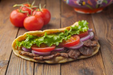 Kavrulmuş et, domates, soğan ve marul mutfak masasında lezzetli taze ev yapımı pita sandviç. 