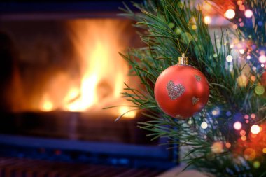 Kalp desenli Noel süs köknar ağacı üzerinde yanan şömine arka plan üzerinde kırmızı top