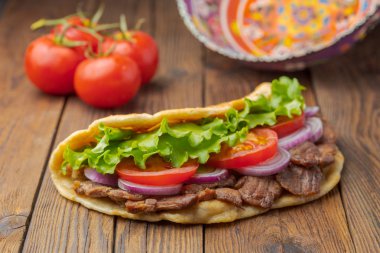 Kavrulmuş et, domates, soğan ve marul mutfak masasında lezzetli taze ev yapımı pita sandviç. 
