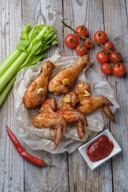 Sos ve sebze ile masada kavrulmuş tavuk kanatları