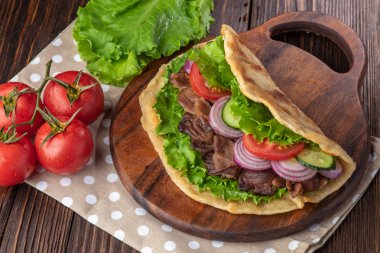 Sığır eti ve sebze lekeli havlu ile ahşap tahta üzerinde taze tortilla sandviçle