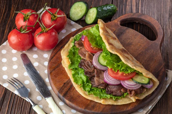 Sığır eti ve sebze lekeli havlu ile ahşap tahta üzerinde taze tortilla sandviçle
