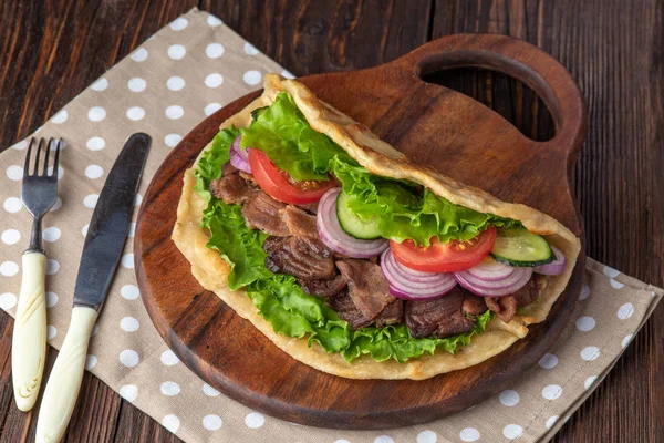Sığır eti ve sebze lekeli havlu ile ahşap tahta üzerinde taze tortilla sandviçle