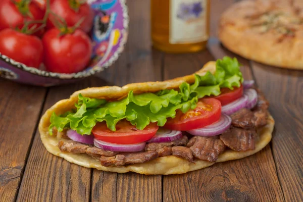 Kavrulmuş et, domates, soğan ve marul mutfak masasında lezzetli taze ev yapımı pita sandviç. 