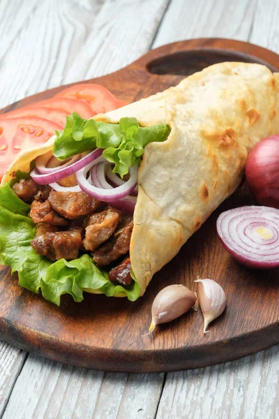 Izgara et ve sebze kesme tahtası üzerinde ev yapımı shawarma sarın