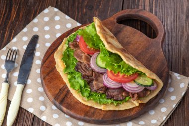 Sığır eti ve sebze lekeli havlu ile ahşap tahta üzerinde taze tortilla sandviçle