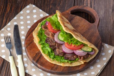 Sığır eti ve sebze lekeli havlu ile ahşap tahta üzerinde taze tortilla sandviçle