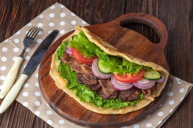 Sığır eti ve sebze lekeli havlu ile ahşap tahta üzerinde taze tortilla sandviçle