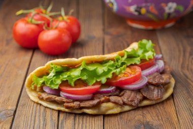 Kavrulmuş et, domates, soğan ve marul mutfak masasında lezzetli taze ev yapımı pita sandviç. 