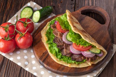 Sığır eti ve sebze lekeli havlu ile ahşap tahta üzerinde taze tortilla sandviçle