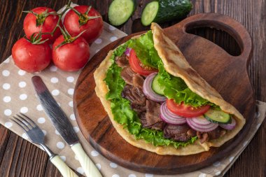 Sığır eti ve sebze lekeli havlu ile ahşap tahta üzerinde taze tortilla sandviçle