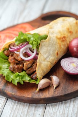 Izgara et ve sebze kesme tahtası üzerinde ev yapımı shawarma sarın