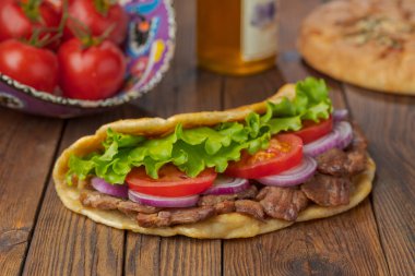 Kavrulmuş et, domates, soğan ve marul mutfak masasında lezzetli taze ev yapımı pita sandviç. 
