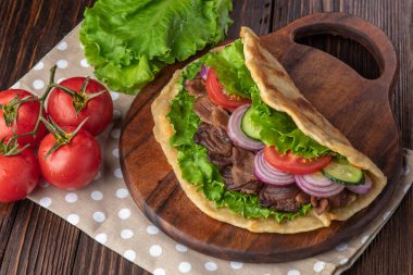 Sığır eti ve sebze lekeli havlu ile ahşap tahta üzerinde taze tortilla sandviçle