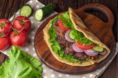 Sığır eti ve sebze lekeli havlu ile ahşap tahta üzerinde taze tortilla sandviçle