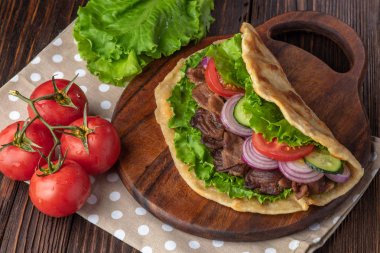 Sığır eti ve sebze lekeli havlu ile ahşap tahta üzerinde taze tortilla sandviçle