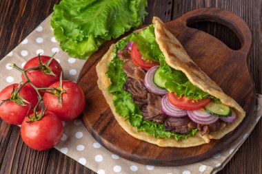 Sığır eti ve sebze lekeli havlu ile ahşap tahta üzerinde taze tortilla sandviçle
