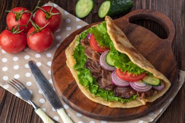 Sığır eti ve sebze lekeli havlu ile ahşap tahta üzerinde taze tortilla sandviçle