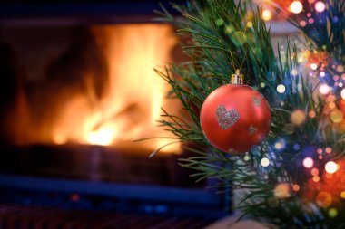 Kalp desenli Noel süs köknar ağacı üzerinde yanan şömine arka plan üzerinde kırmızı top