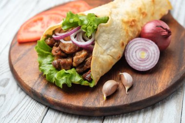 Izgara et ve sebze kesme tahtası üzerinde ev yapımı shawarma sarın