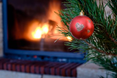 Kırmızı top bauble şömine arka planda şenlikli Noel köknar ağacı asılı