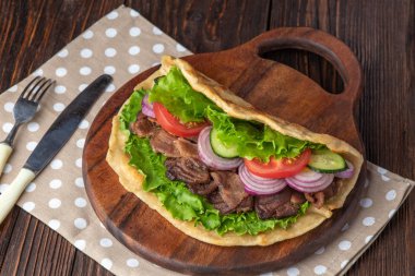 Sığır eti ve sebze lekeli havlu ile ahşap tahta üzerinde taze tortilla sandviçle