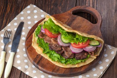 Sığır eti ve sebze lekeli havlu ile ahşap tahta üzerinde taze tortilla sandviçle