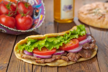 Kavrulmuş et, domates, soğan ve marul mutfak masasında lezzetli taze ev yapımı pita sandviç. 