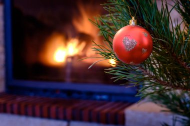 Kırmızı top bauble şömine arka planda şenlikli Noel köknar ağacı asılı