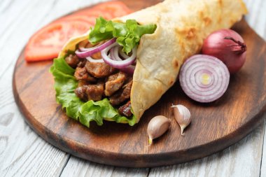 Izgara et ve sebze kesme tahtası üzerinde ev yapımı shawarma sarın