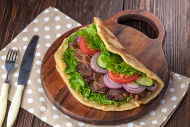 Sığır eti ve sebze lekeli havlu ile ahşap tahta üzerinde taze tortilla sandviçle