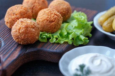 Turşu ve sos ile masada ahşap tahta üzerinde kızarmış falafel topları