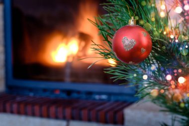 Kalp desenli Noel süs köknar ağacı üzerinde yanan şömine arka plan üzerinde kırmızı top
