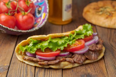 Kavrulmuş et, domates, soğan ve marul mutfak masasında lezzetli taze ev yapımı pita sandviç. 