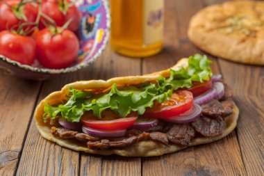 Kavrulmuş et, domates, soğan ve marul mutfak masasında lezzetli taze ev yapımı pita sandviç. 