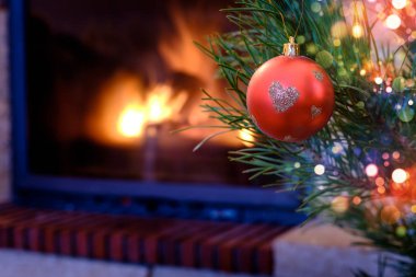 Kalp desenli Noel süs köknar ağacı üzerinde yanan şömine arka plan üzerinde kırmızı top