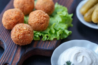 Turşu ve sos ile masada ahşap tahta üzerinde kızarmış falafel topları
