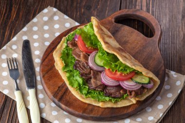 Sığır eti ve sebze lekeli havlu ile ahşap tahta üzerinde taze tortilla sandviçle
