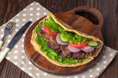Sığır eti ve sebze lekeli havlu ile ahşap tahta üzerinde taze tortilla sandviçle