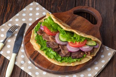 Sığır eti ve sebze lekeli havlu ile ahşap tahta üzerinde taze tortilla sandviçle