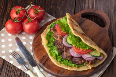 Sığır eti ve sebze lekeli havlu ile ahşap tahta üzerinde taze tortilla sandviçle