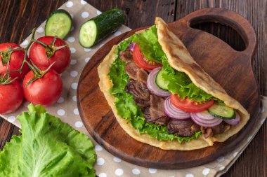 Sığır eti ve sebze lekeli havlu ile ahşap tahta üzerinde taze tortilla sandviçle