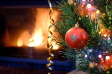 Kalp desenli Noel süs köknar ağacı üzerinde yanan şömine arka plan üzerinde kırmızı top