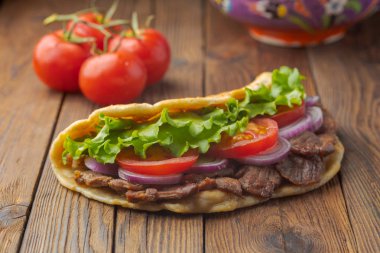 Kavrulmuş et, domates, soğan ve marul mutfak masasında lezzetli taze ev yapımı pita sandviç. 