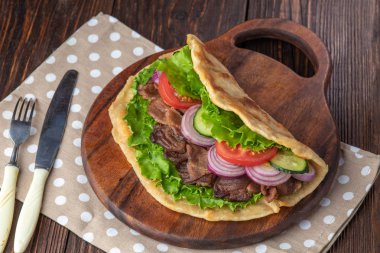 Sığır eti ve sebze lekeli havlu ile ahşap tahta üzerinde taze tortilla sandviçle