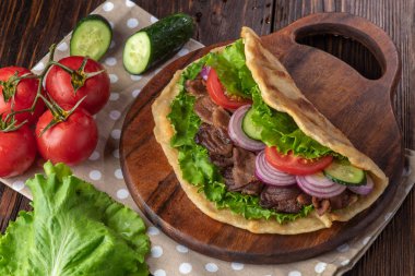 Sığır eti ve sebze lekeli havlu ile ahşap tahta üzerinde taze tortilla sandviçle