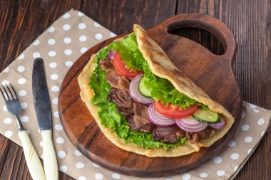 Sığır eti ve sebze lekeli havlu ile ahşap tahta üzerinde taze tortilla sandviçle