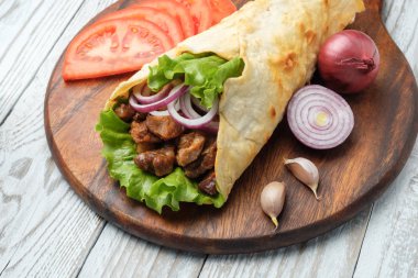 Izgara et ve sebze kesme tahtası üzerinde ev yapımı shawarma sarın